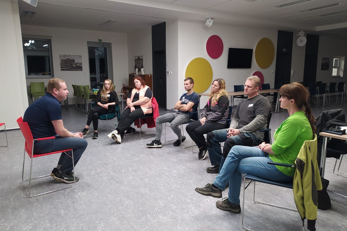 Lektor rozebírá situaci s účastníky sedícími v kruhu